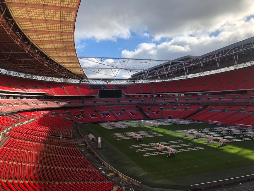An exterior view of Wembley Stadium during the evening, featuring a large digital display sign with the Wembley logo and the word 'CONNECTED' against a teal background. The stadium's architectural det